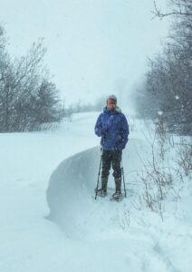 Kate standing in the middle of a snow storm in snow shoes.